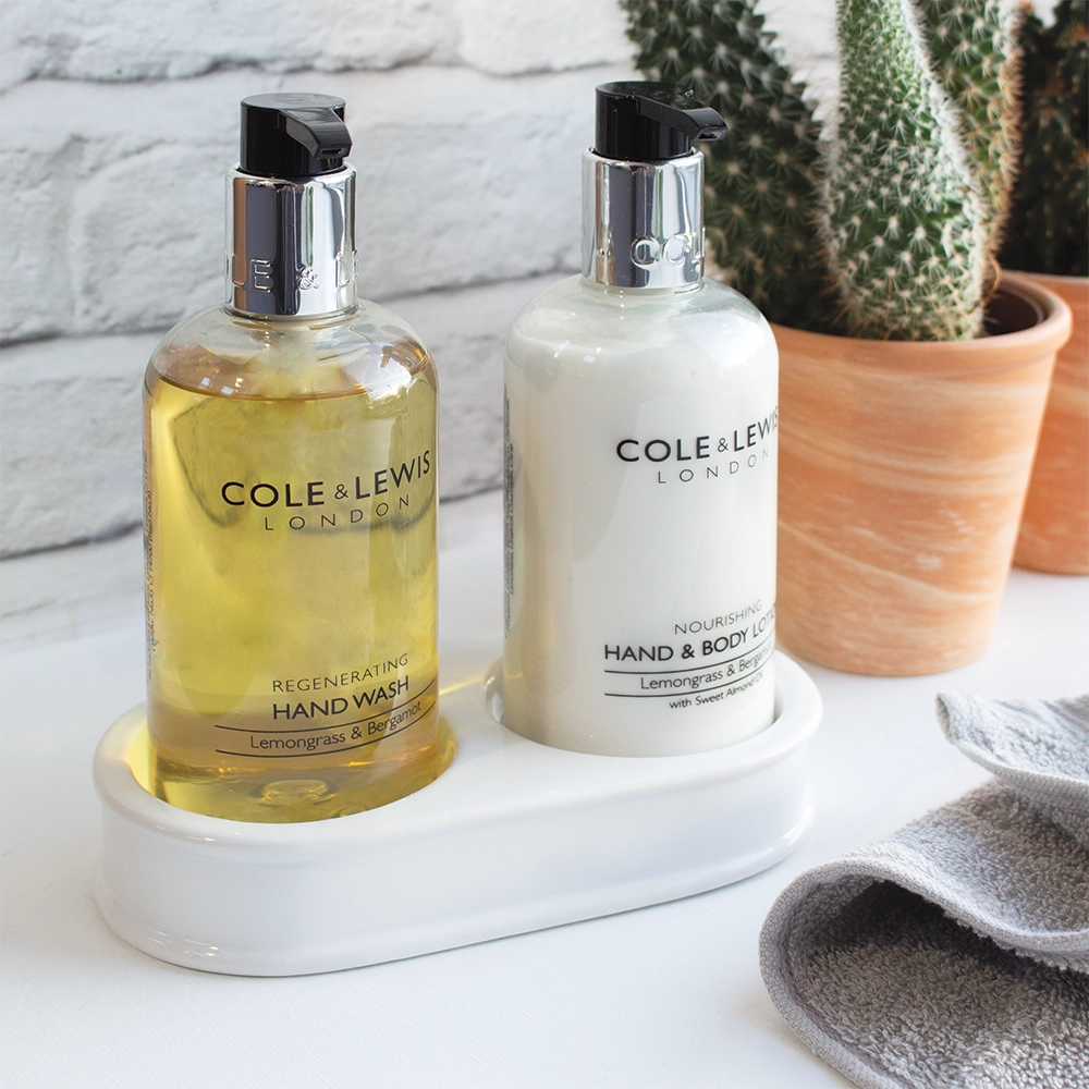 A ceramic twin-compartment tray holding two 300ml toiletry bottles, showcasing an elegant and organized bathroom setup.