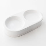 A high-gloss white ceramic tray with two compartments, designed to neatly hold and display toiletry bottles or other small items.